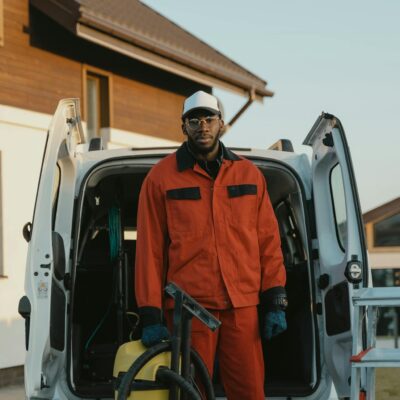 Man in Orange Jacket Standing Beside White Van